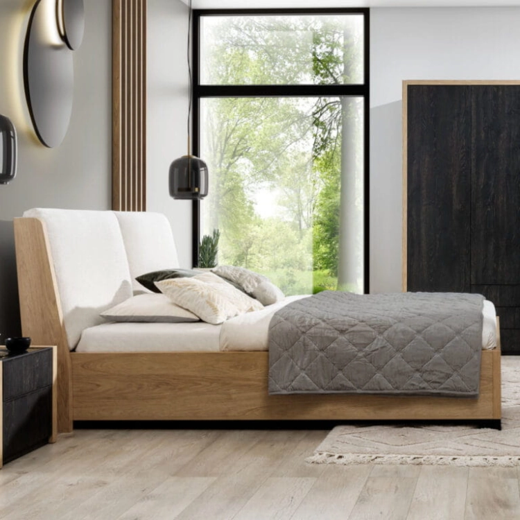 Łóżko MODELLO z tapicerowanym zagłówkiem New Elegance. Łóżko z miękkimi poduchami na odchylonym wezgłowiu, w tkaninie Positano o strukturze delikatnej plecionki z kolekcji Davisa.