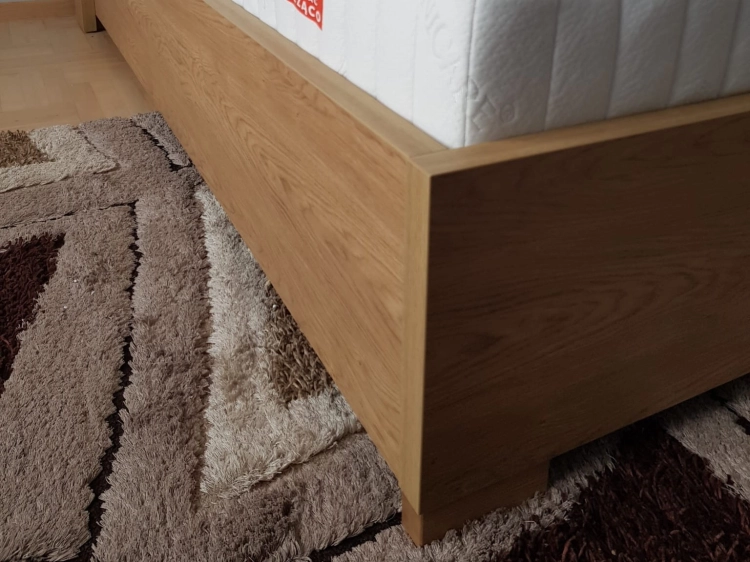 Łóżko MODELLO z tapicerowanym zagłówkiem New Elegance. Łóżko z miękkimi poduchami na odchylonym wezgłowiu, w tkaninie Positano 87 o strukturze delikatnej plecionki z kolekcji Davisa. materac Hybrid 3000 Fey
